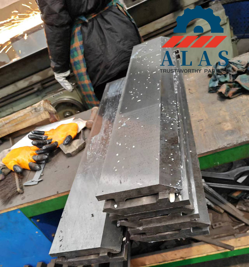 In-House Manufacturing of Precision Sheet Metal Brake Dies Precision press brake punch dies stacked on a workbench during the final grinding and manufacturing process at the ALAS factory floor
