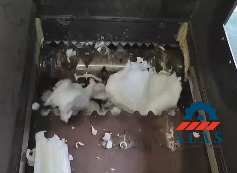 Inside look of a single shaft shredder cutting chamber processing plastic films against a serrated counter knife