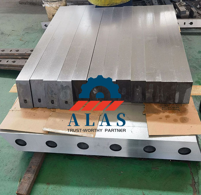 Heavy alloy steel gantry scrap shear blade segments stacked in manufacturing workshop