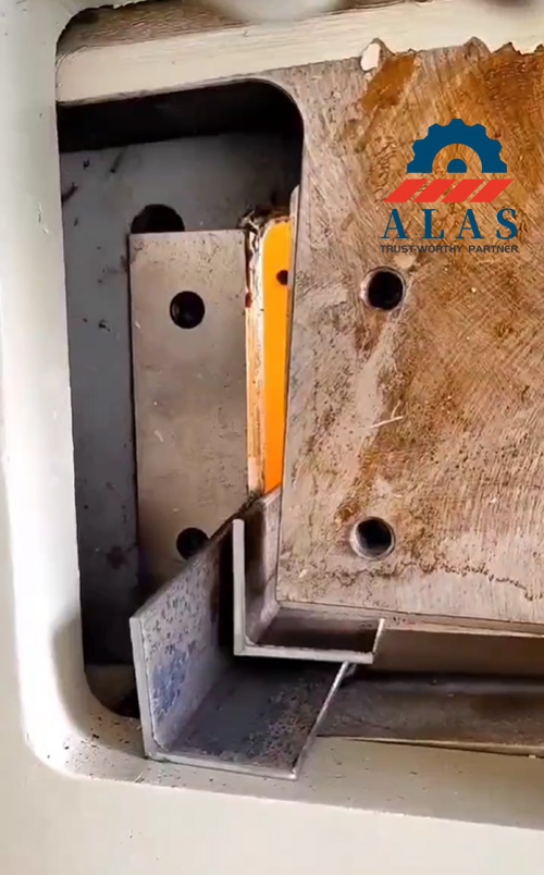 Close-up of 90-degree angle iron cutting blade installed in a hydraulic ironworker machine before shearing operation.