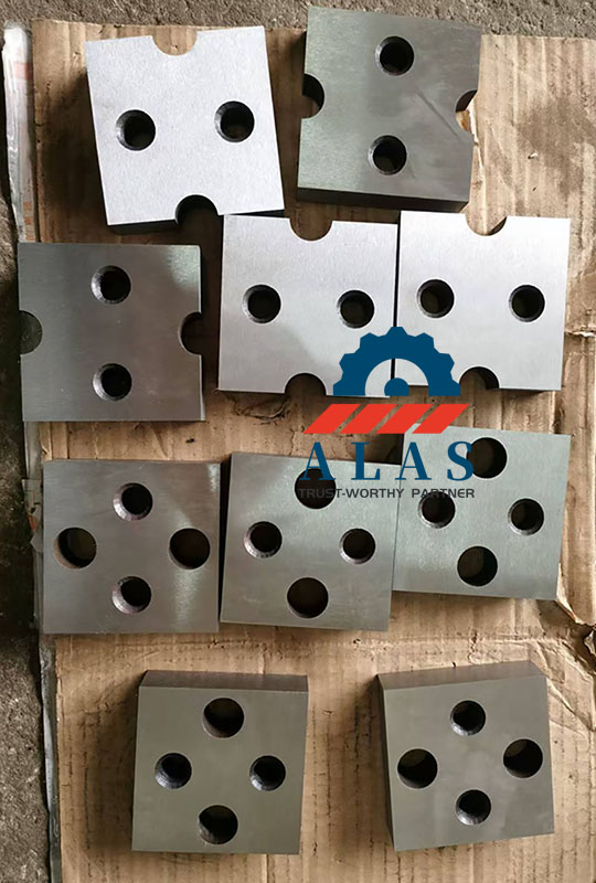 An assortment of multi-specification industrial rebar cutter blades including 2-hole rectangular and 4-hole square geometry structures flat-laid in the ALAS warehouse.