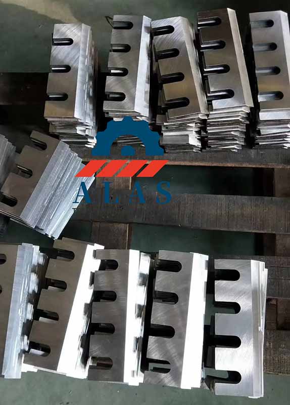Finished batch inventory of precision-ground commercial wood chipper knives stacked on the manufacturing floor.