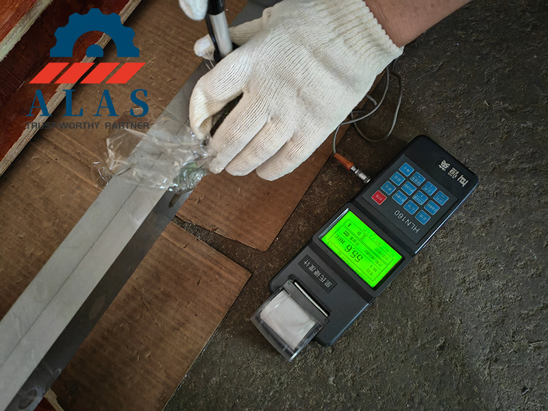 Quality inspection of an industrial metal cutting shear blade undergoing hardness testing to verify 55.6 HRC