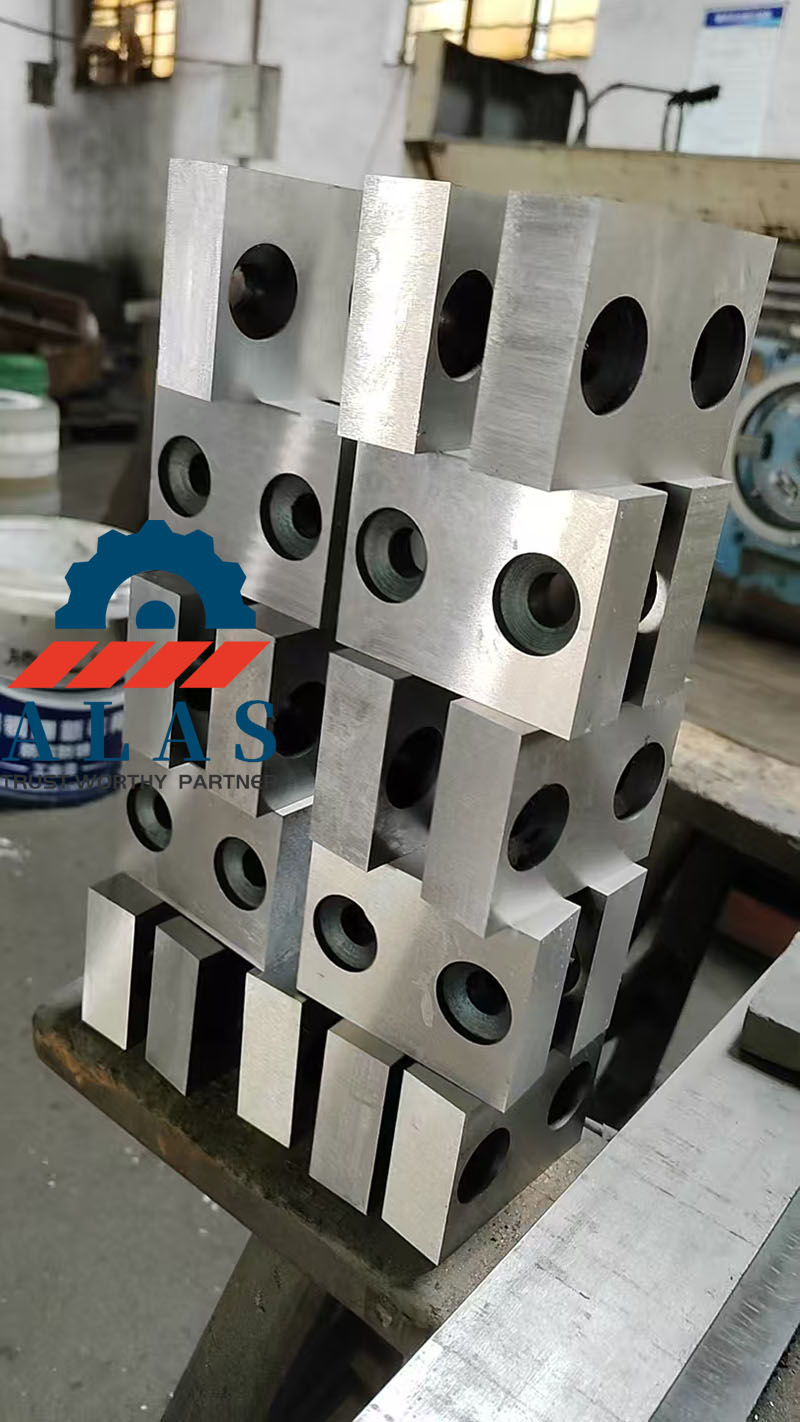 Heavy-duty rectangular rebar cutter blades with double holes stacked in a metal processing factory