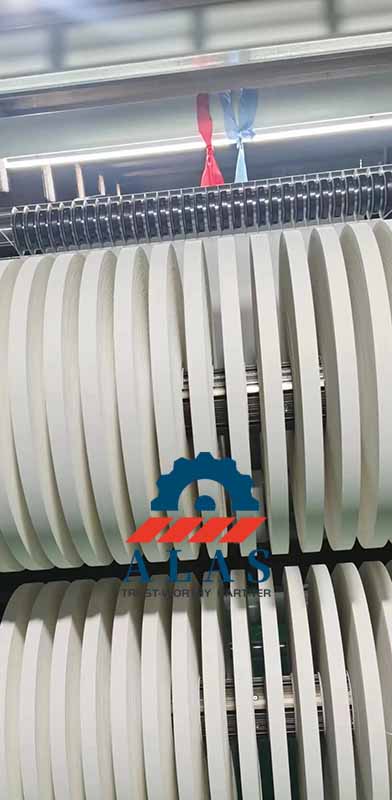 An automated adhesive tape rewinding and slitting machine equipped with precision rotary slitter knives processing white tape rolls.