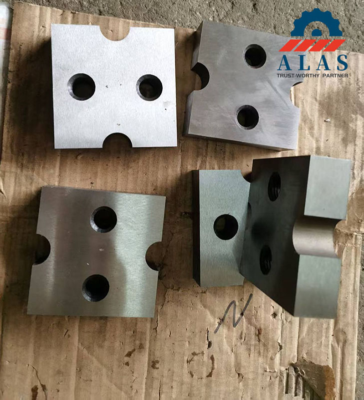Custom manufactured tool steel bar cutter blade blocks featuring localized edge notches and internal countersunk mounting holes.