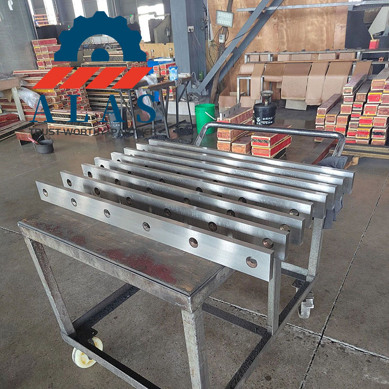 Finished rectangular lower shear blades with precision-bored counterbore holes stacked for hydraulic swing beam shearing machines.