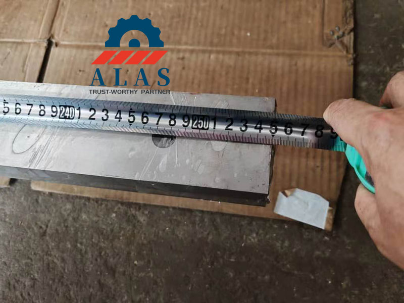 Measuring the length tolerance of a hydraulic shear blade with a steel tape measure during factory inspection