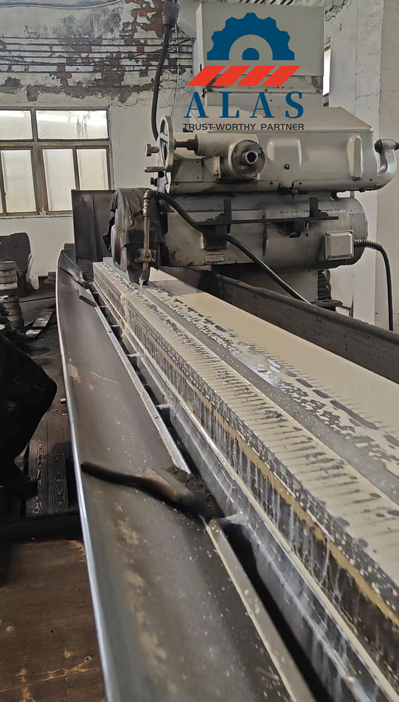 ALAS Heavy-Duty Machining: Premium Grinding Capabilities for Extra-Long Custom Shear Knives A heavy-duty long-bed surface grinding machine processing an extra-long industrial shearing machine blade in factory