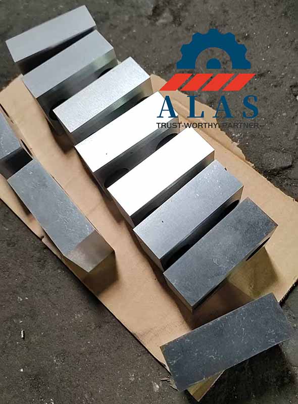 A series of heavy-duty forged alloy steel bar cropper knives highlighting thick monolithic profiles and dual counter-bored mounting points.