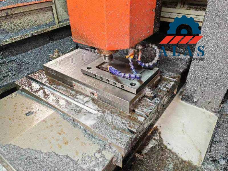 CNC machining center processing high-precision metal stamping die component with coolant
